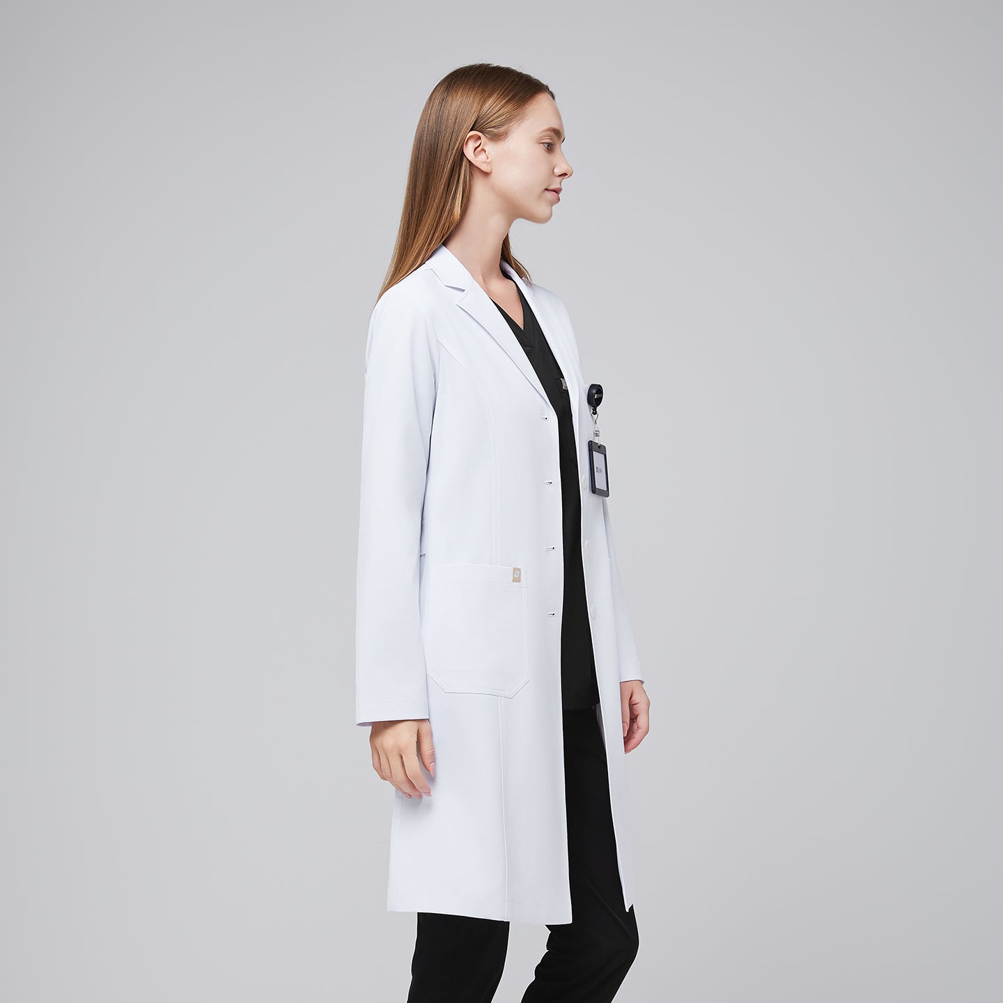 Female doctor in a white lab coat and black scrubs, side profile with an ID badge,White