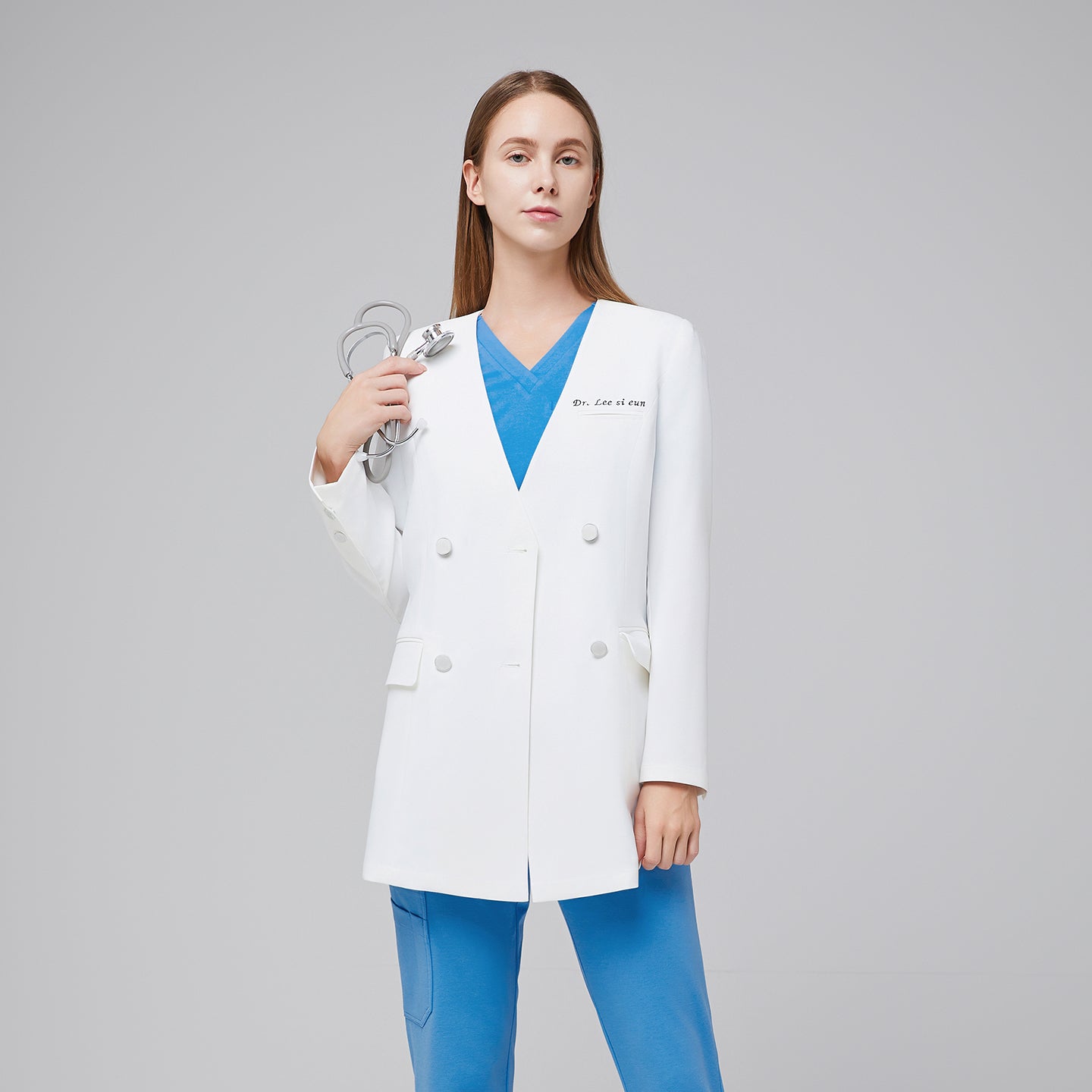 Female doctor wearing a white double-breasted lab coat with embroidered name, styled with blue scrubs, showcasing a clean and professional look,White