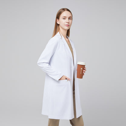 Woman in a white lab coat holding a brown cup with 'ZENIR' branding, wearing beige scrubs underneath,White