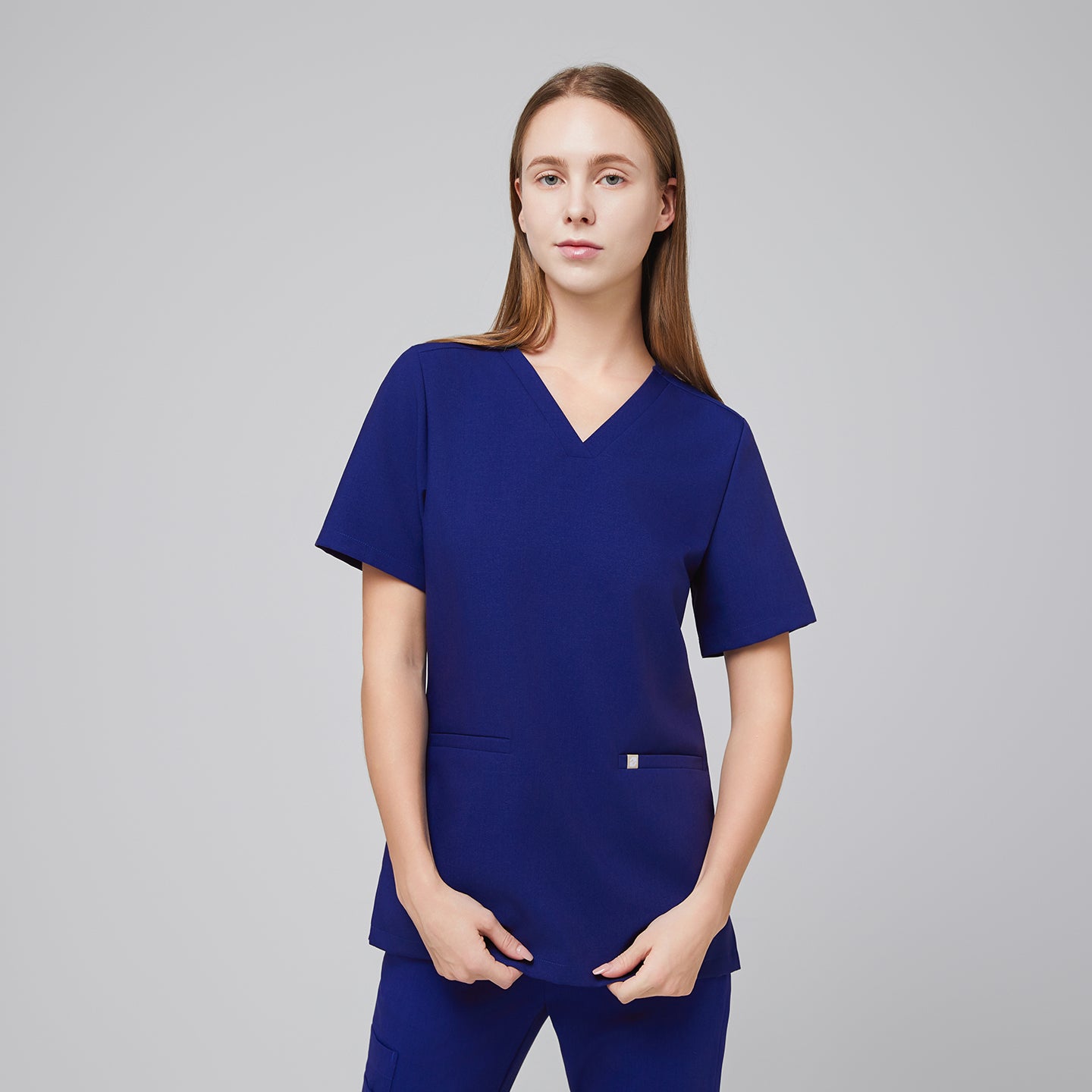 Woman wearing a navy blue V-neck scrub top with two front pockets and matching scrub pants,Admiral Blue