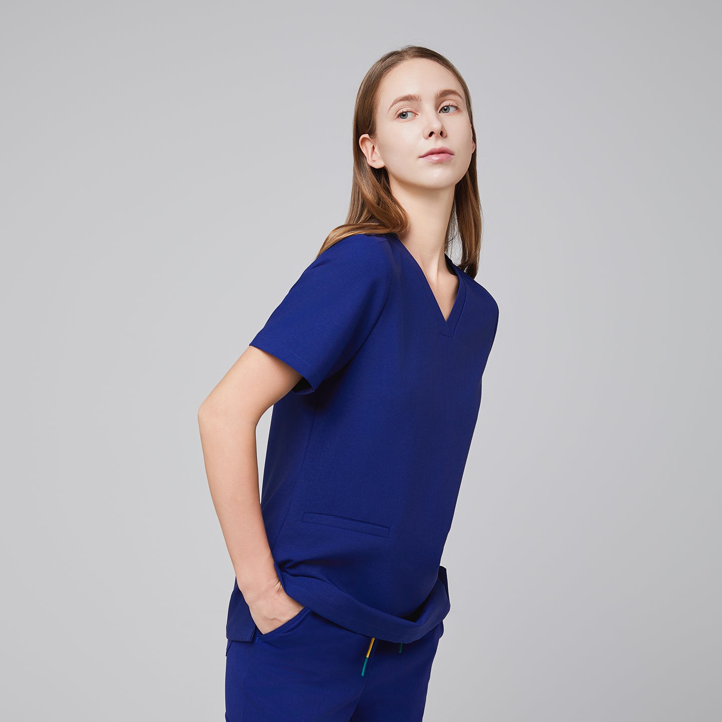 Model in navy blue double pocket V-neck scrub top and matching scrub pants,Admiral Blue