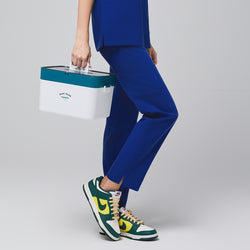 Image of Female wearing blue scrub pants, holding a medical box, paired with green, yellow, and white sneakers,Admiral Blue