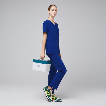 Female model in blue scrub top and pants, holding a white and teal medical box, paired with green, yellow, and white sneakers,Admiral Blue