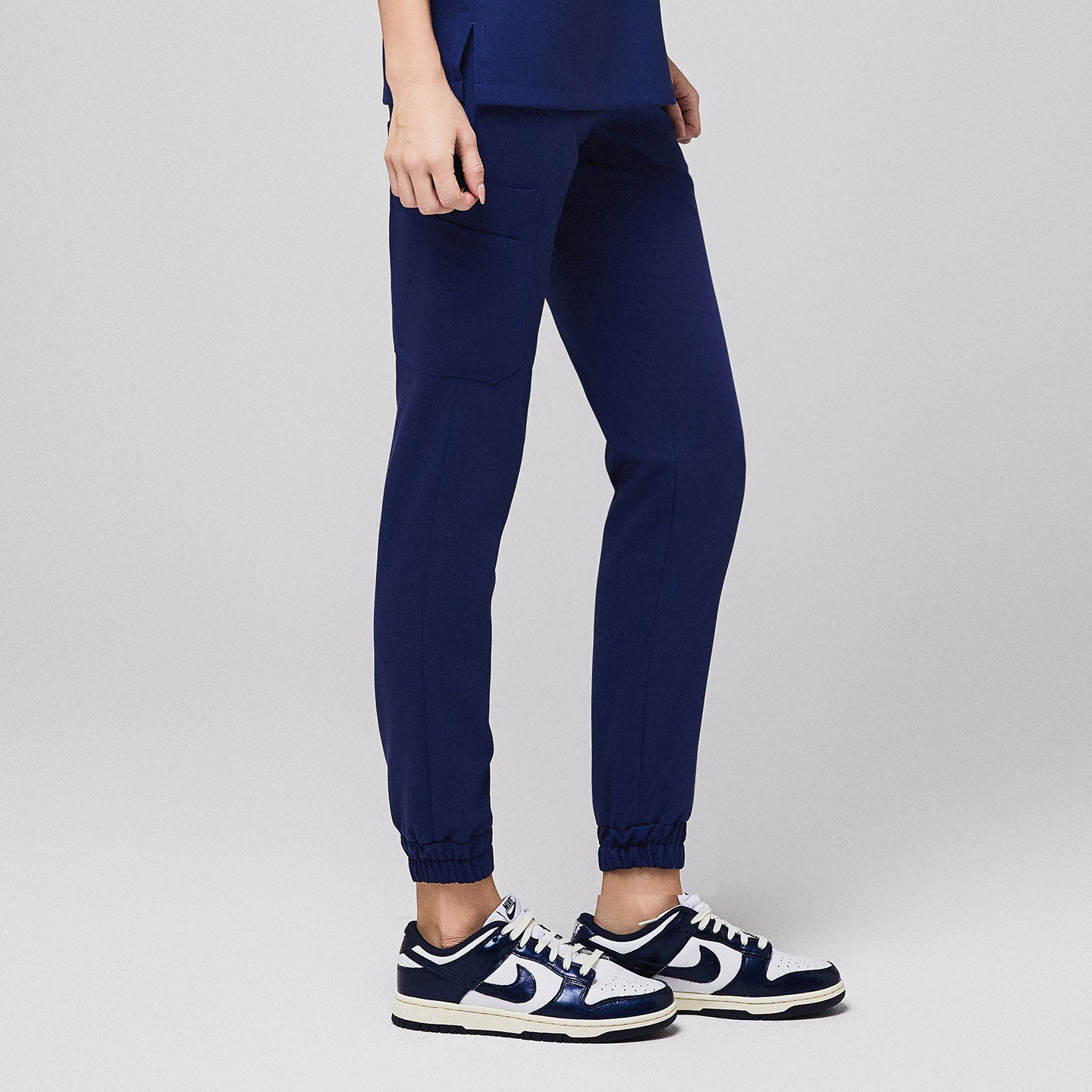 Medical professional wearing jogger-style scrub pants with side pocket and sneakers,Admiral Blue