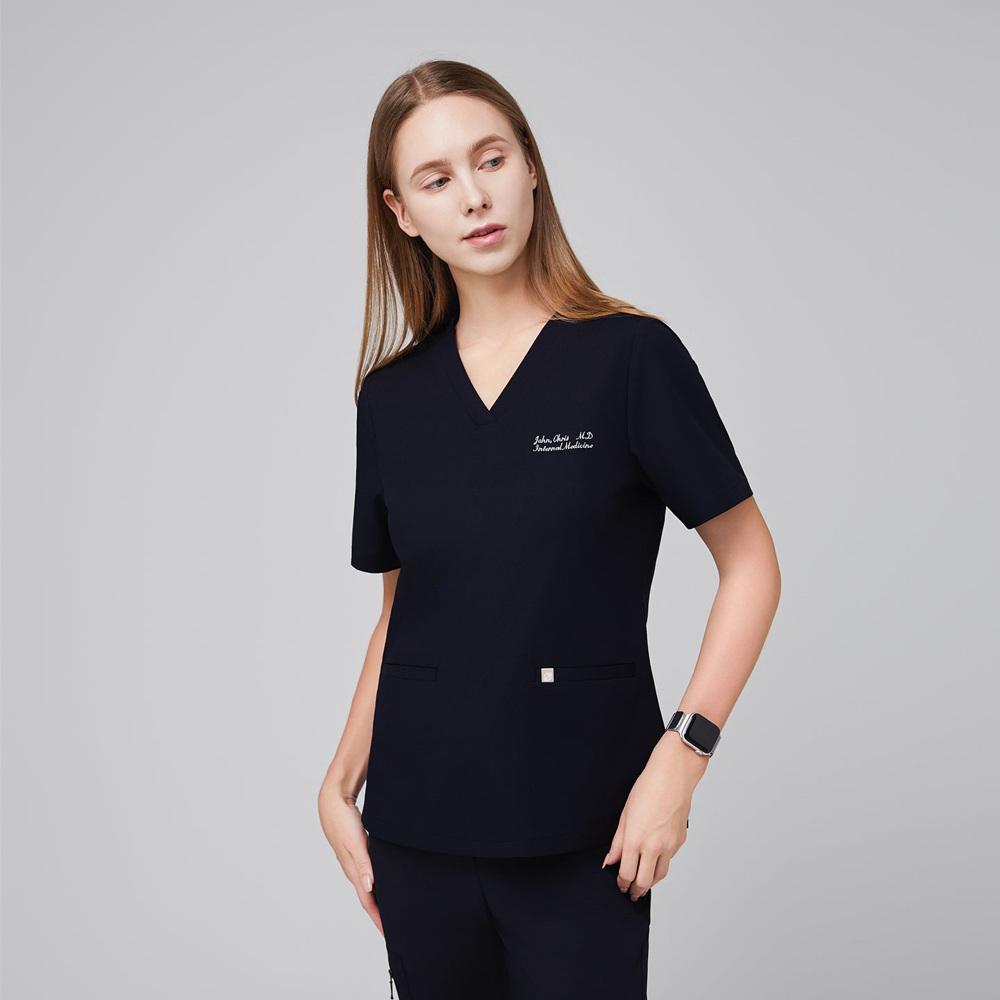 Model wearing an eco navy double pocket scrub top with embroidered name and matching scrub pants,Eco Navy