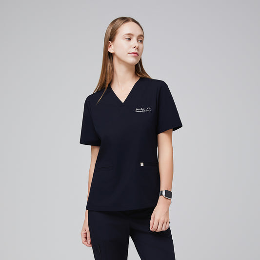 Model wearing an eco navy double pocket scrub top with embroidered name and matching scrub pants,Eco Navy