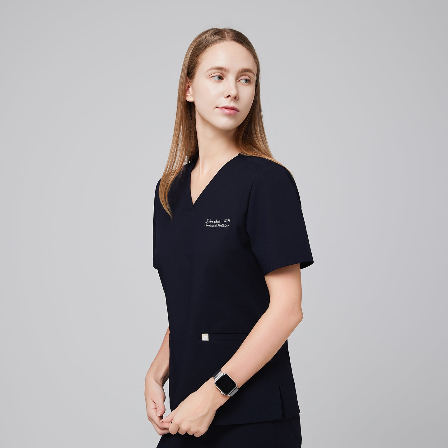 Model in an eco navy double pocket scrub top with embroidered name and matching scrub pants,Eco Navy