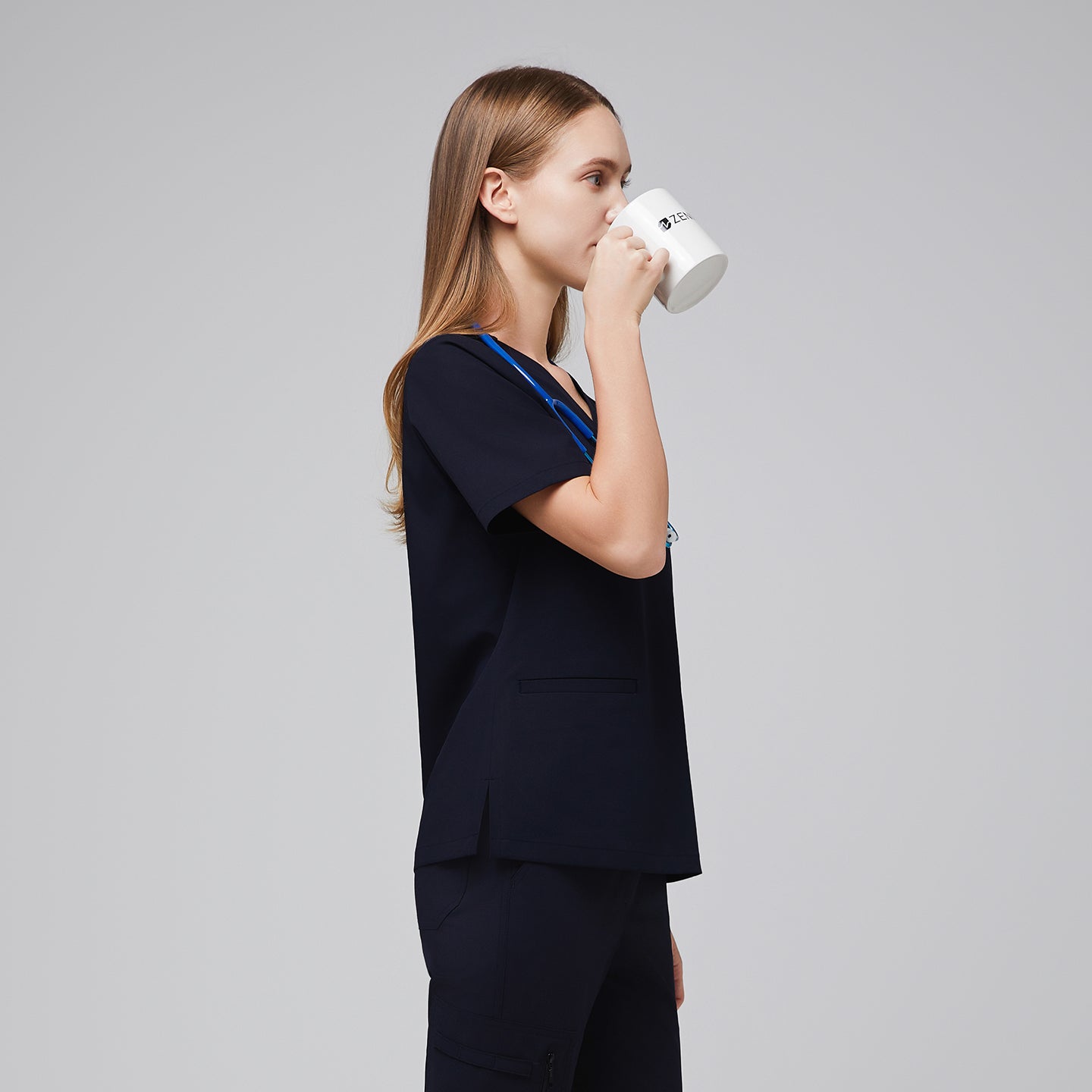 Model in an eco navy double pocket scrub top drinking from a mug and wearing matching scrub pants,Eco Navy