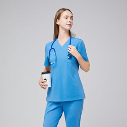 Image of Woman in an aqua blue scrub set holding a coffee cup, with a stethoscope around her neck, looking confidently to the side.,Aqua Blue