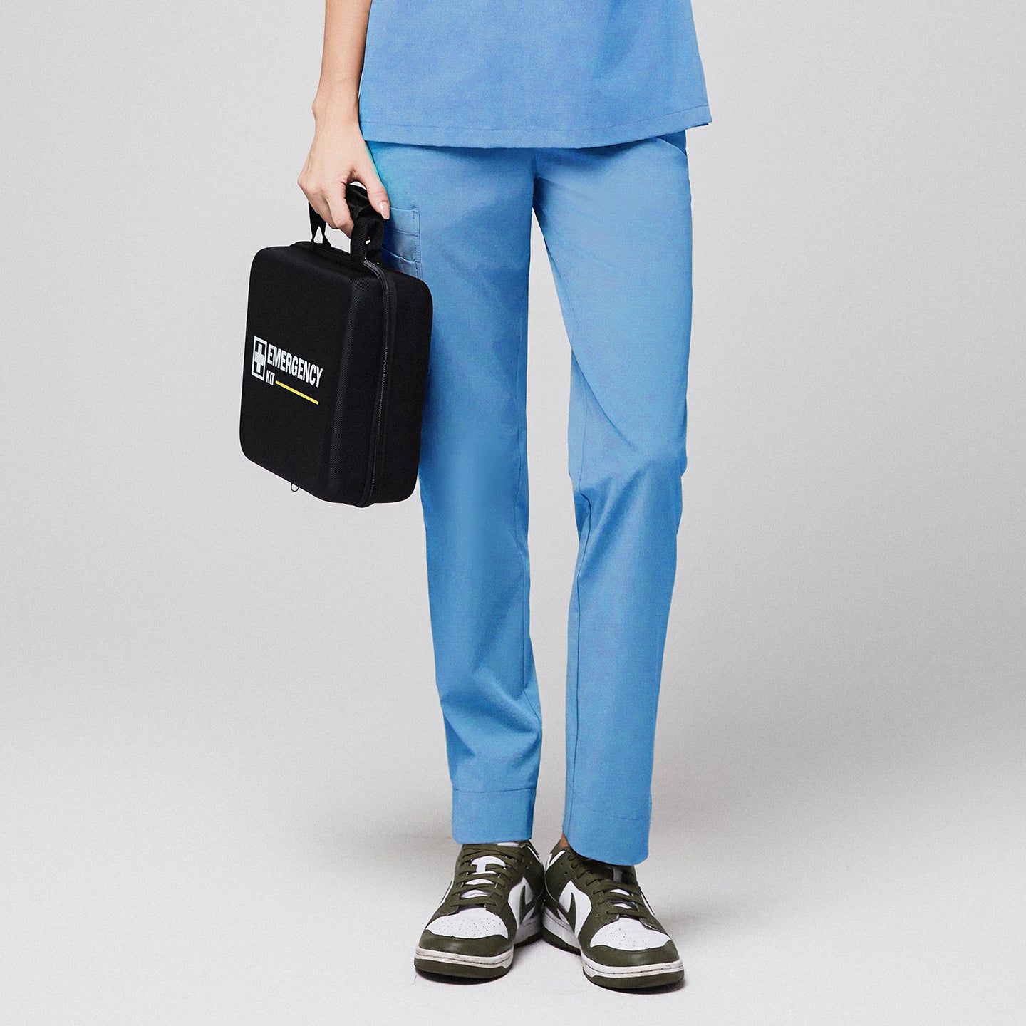 Aqua blue scrub pants with split hem and side pocket, holding a black emergency kit, paired with green and white sneakers,Aqua Blue