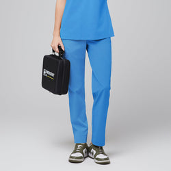 Image of Close-up of a model wearing aqua blue scrub pants ft, holding a black emergency kit against a grey background,Aqua Blue