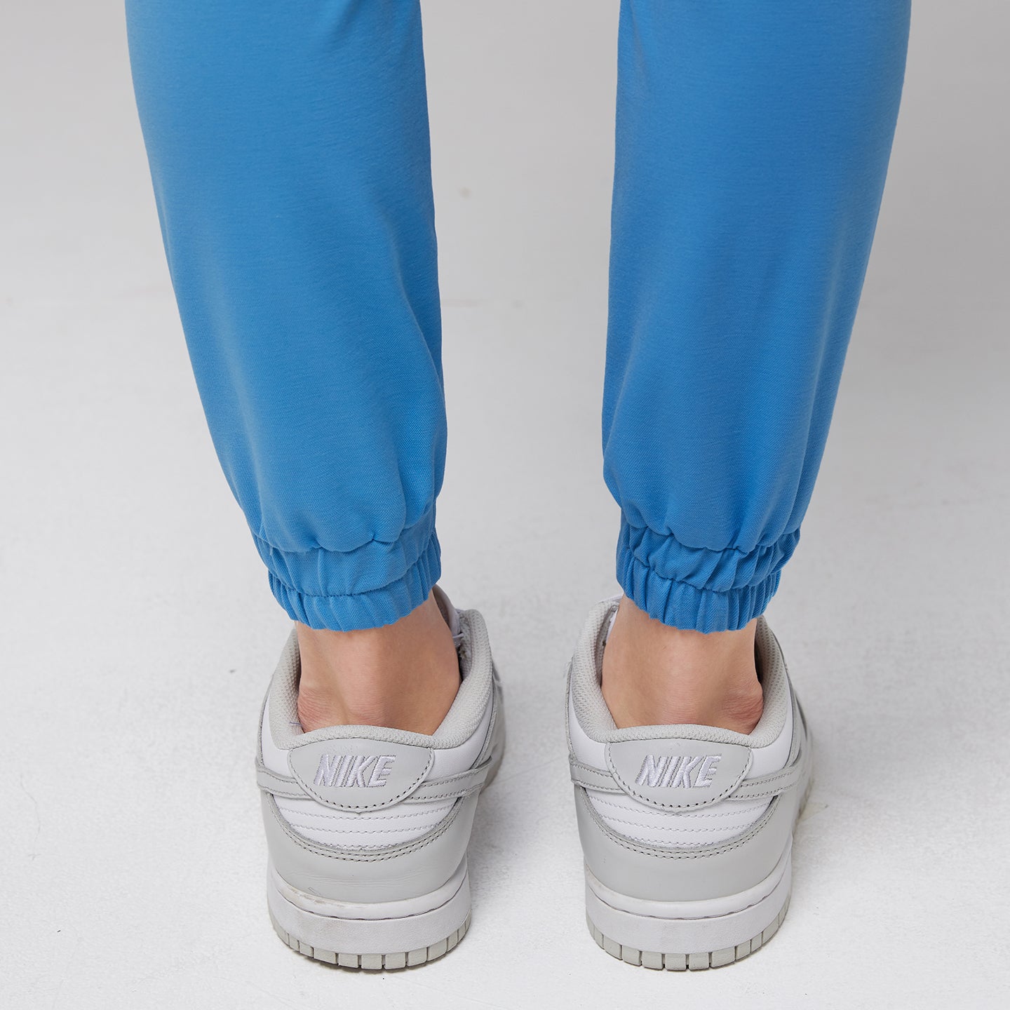 Close-up of elastic ankle cuffs on aqua blue jogger scrub pants paired with white Nike sneakers,Aqua Blue