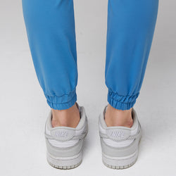 Image of Close-up of elastic ankle cuffs on aqua blue jogger scrub pants paired with white Nike sneakers,Aqua Blue