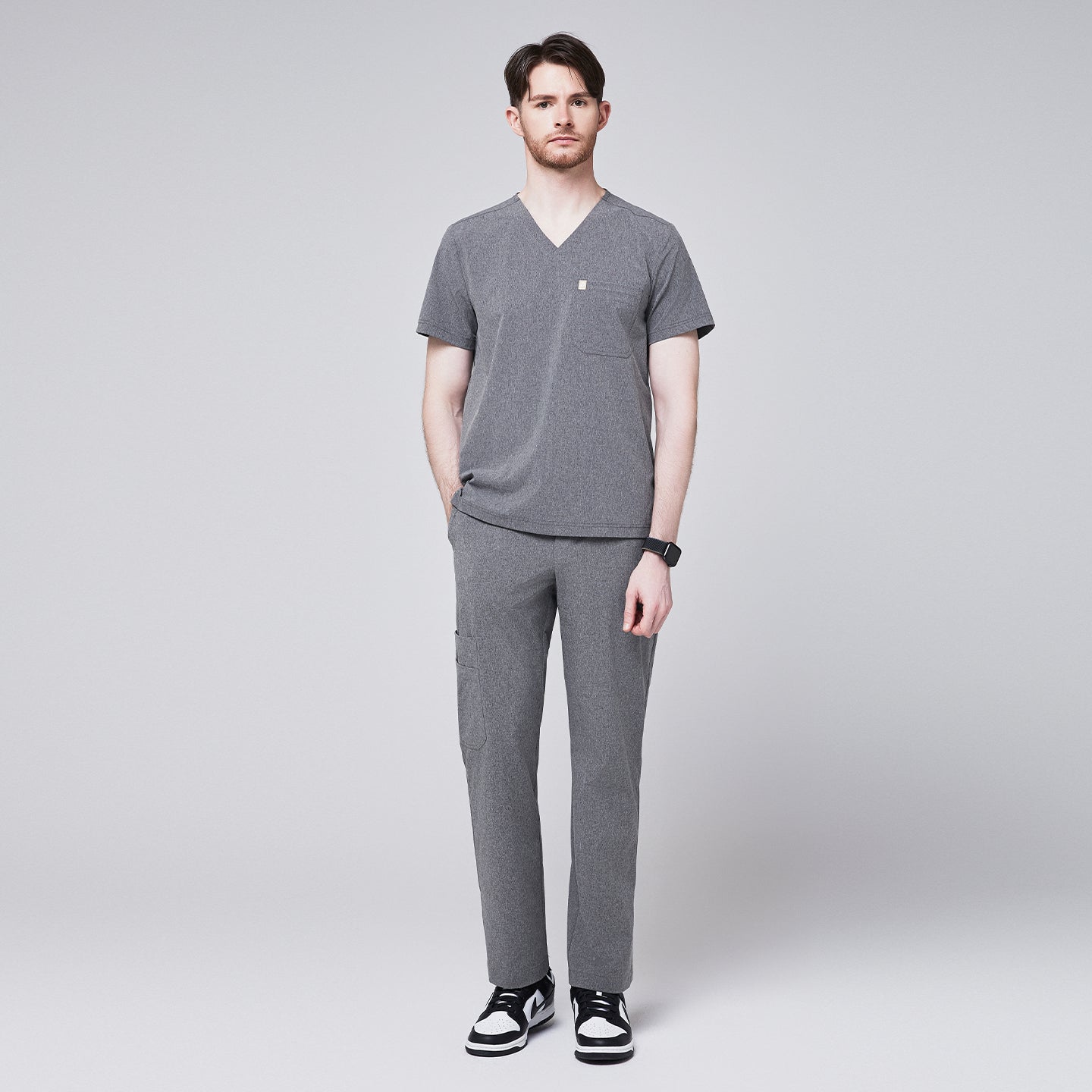 Man wearing ash gray scrubs with a V-neck and a single chest pocket, paired with matching pants and black sneakers,Ash Gray