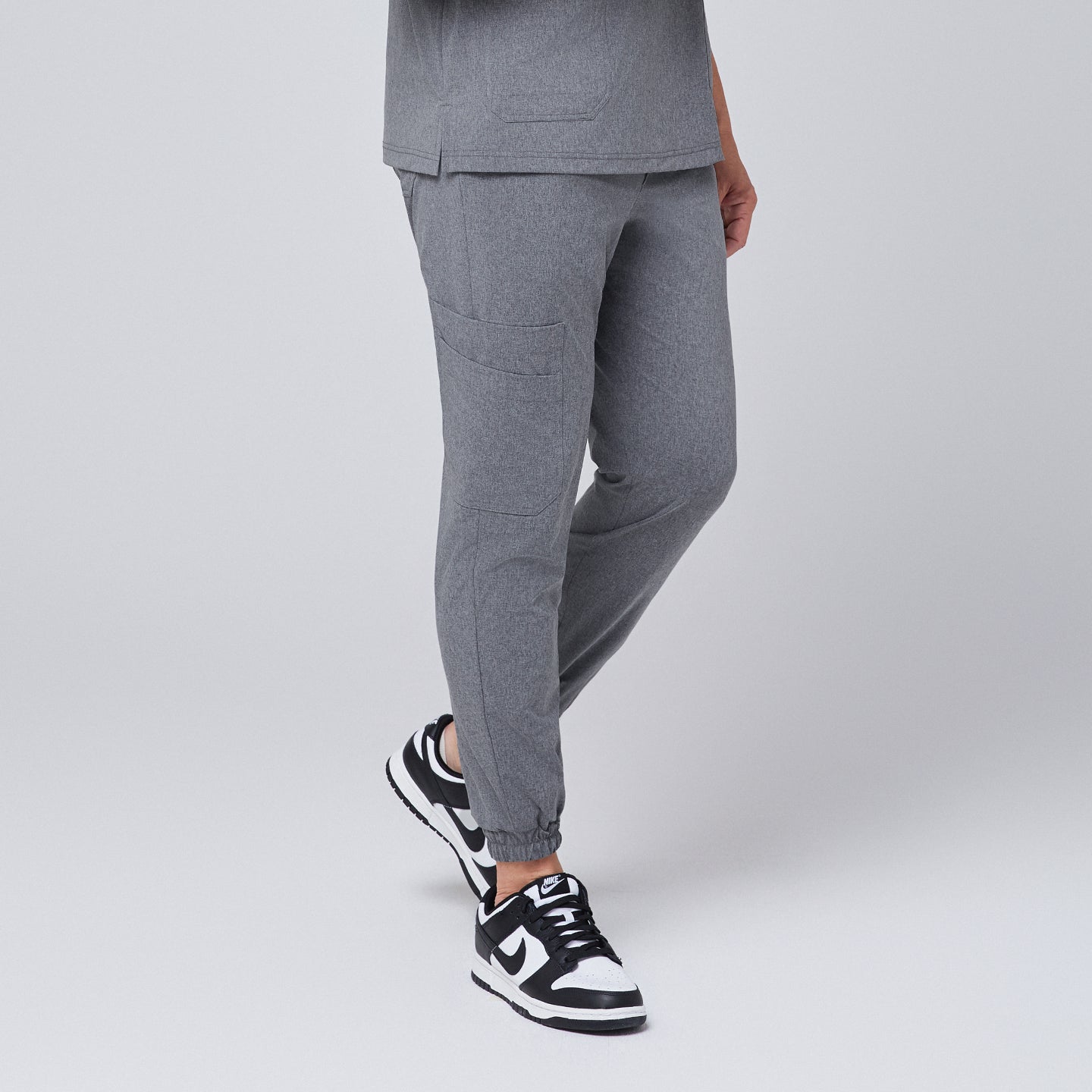 Ash gray jogger scrub pants with side pocket and elastic cuffs, paired with black and white sneakers,Ash Gray