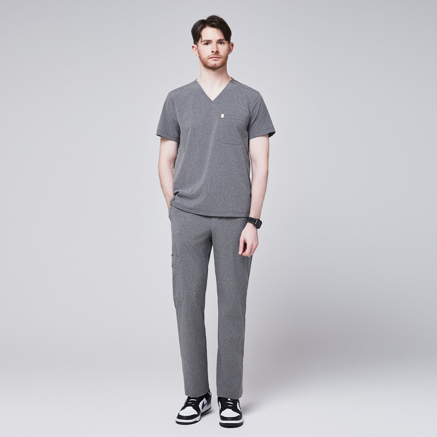 Man wearing ash gray scrub pants with a straight-leg fit and side pocket, paired with a matching V-neck scrub top and black-and-white sneakers,Ash Gray