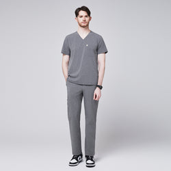 Image of Man wearing ash gray scrub pants with a straight-leg fit and side pocket, paired with a matching V-neck scrub top and black-and-white sneakers,Ash Gray