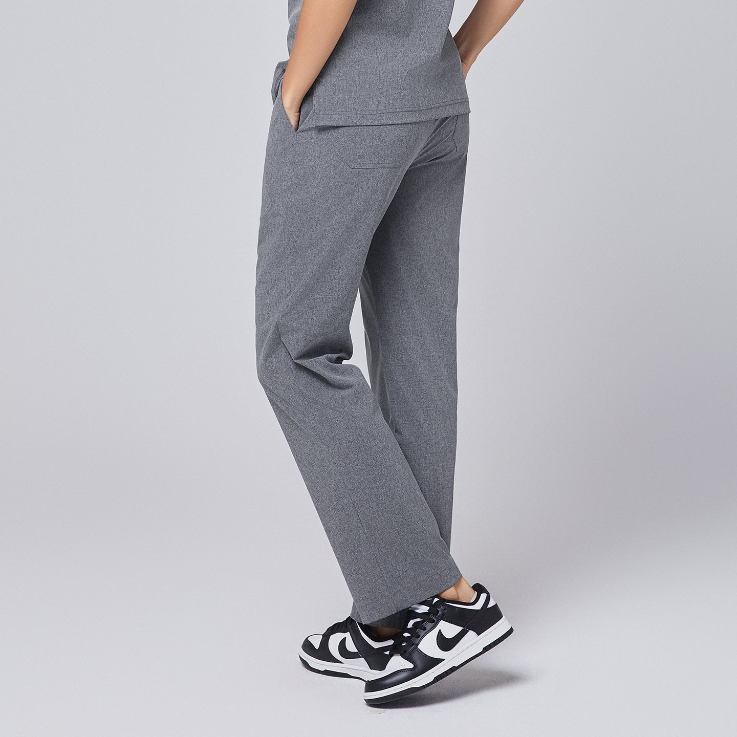 Back view of ash gray straight-leg scrub pants with a split hem, paired with black-and-white sneakers on a neutral background,Ash Gray