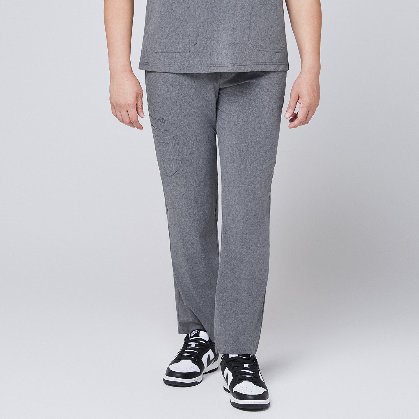 Male model wearing ash gray relaxed-fit scrub pants with a straight-leg design, paired with black and white sneakers, showcasing a professional medical attire style,Ash Gray