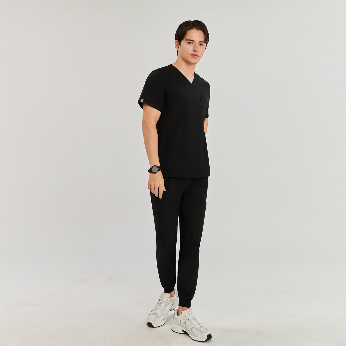 Man in black Zenir scrub top with chest pocket, standing and looking at the camera, full-body view,Black
