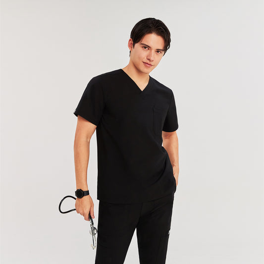 Man wearing a scrub top, holding a stethoscope, with a hand in the pocket and standing in a relaxed pose, Black