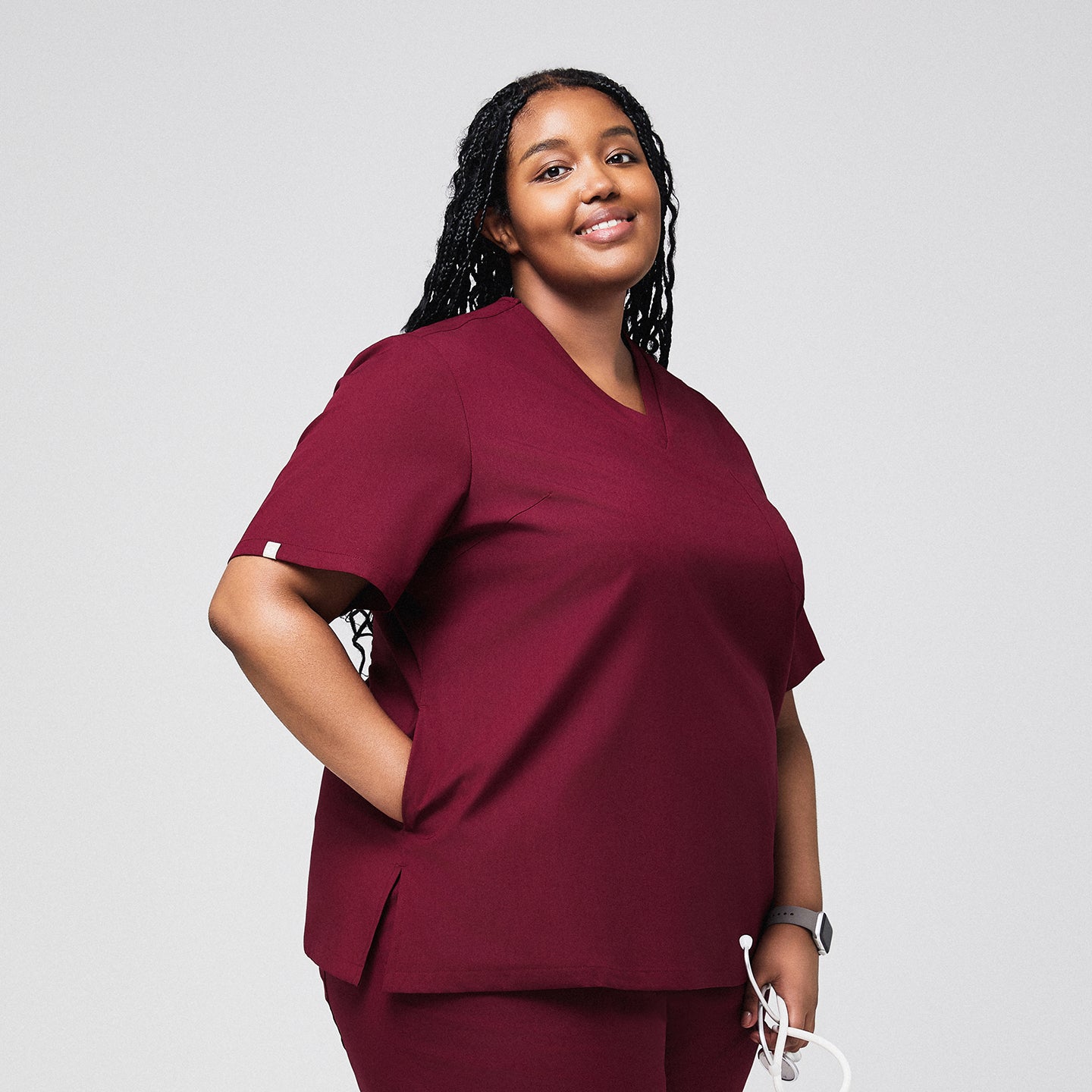 Plus-size model wearing a burgundy 3-pocket scrub top, holding a stethoscope, displaying a comfortable and functional fit for healthcare professionals,Burgundy