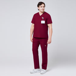 Image of Man wearing burgundy V-neck scrub top and 8-pocket straight scrub pants, accessorized with a name badge and paired with white sneakers,Burgundy