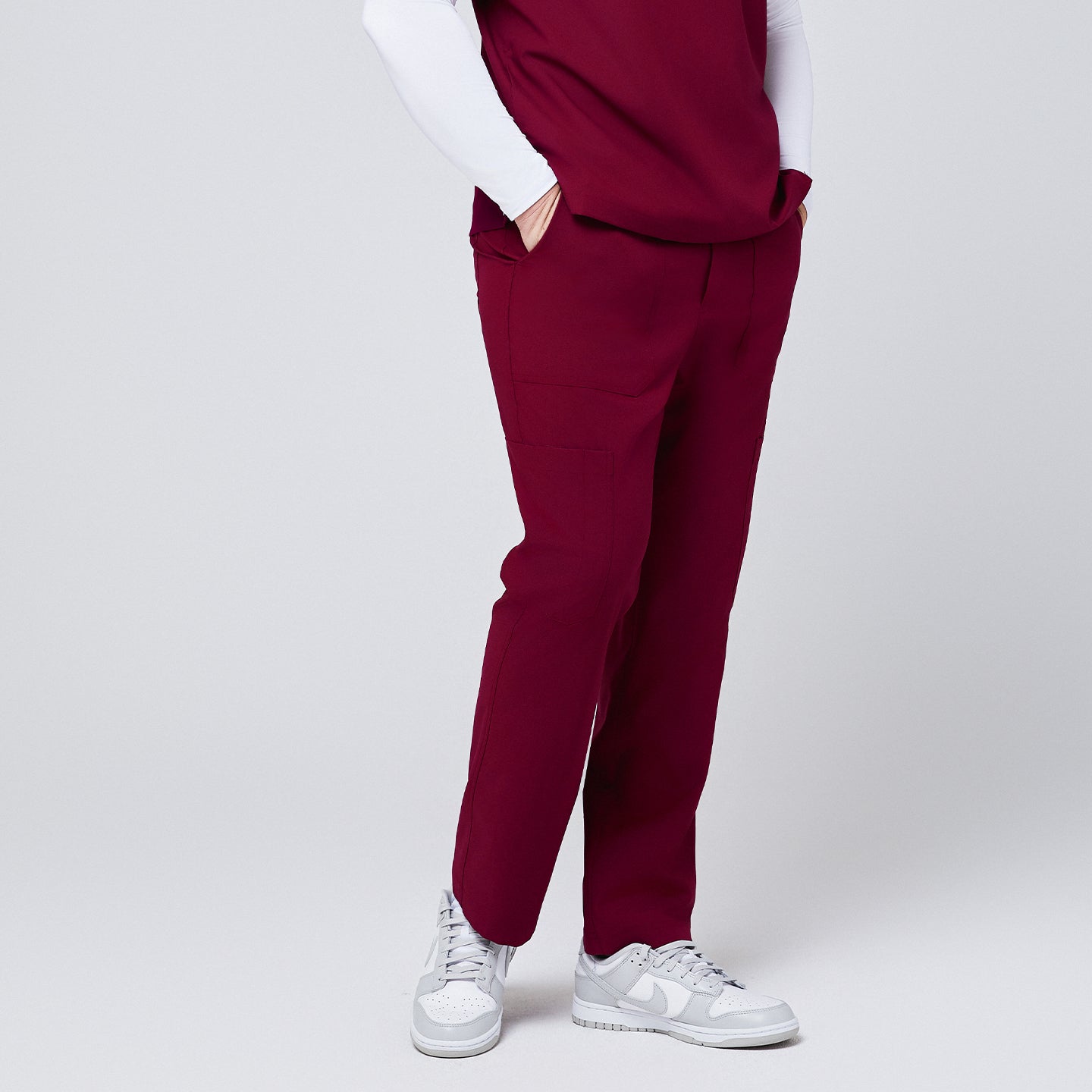 Side view of burgundy 8-pocket straight scrub pants with functional pockets, paired with white sneakers,Burgundy