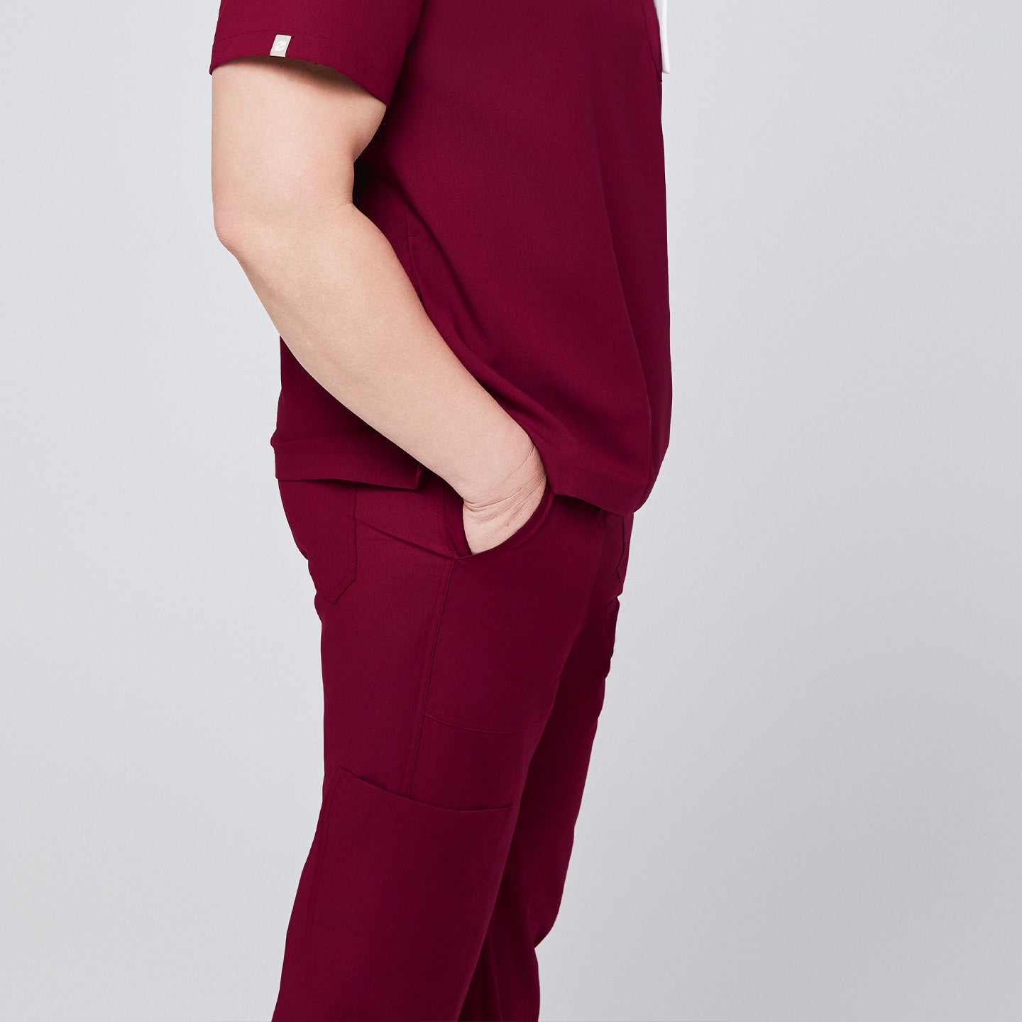 Side profile of burgundy scrub pants with functional pockets and matching scrub top, showcasing a clean and professional design,Burgundy