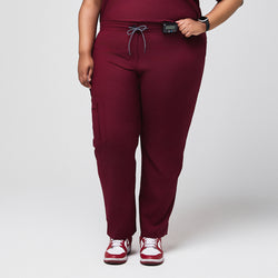 Image of Burgundy scrub pants with zipper pocket and split hem, paired with red sneakers,Burgundy