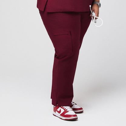 Side view of burgundy scrub pants with zipper pocket and split hem, paired with red sneakers,Burgundy