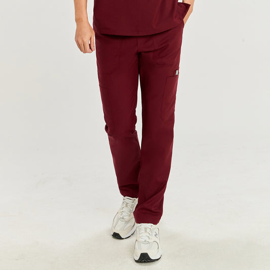 Front view of a model wearing burgundy straight scrub pants with zipper details and a matching top, paired with white athletic shoes,Burgundy