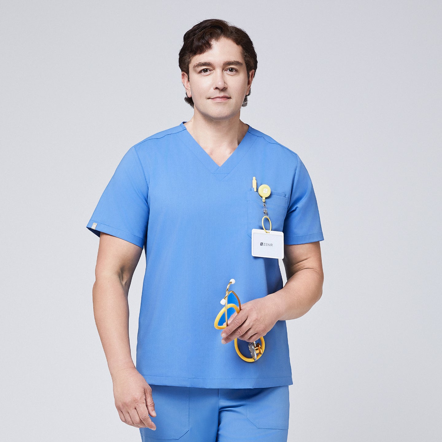 Male healthcare professional wearing a ceil blue V-neck scrub set with a chest pocket holding a pen and ID badge, holding a yellow stethoscope for a functional and professional appearance,Ceil Blue