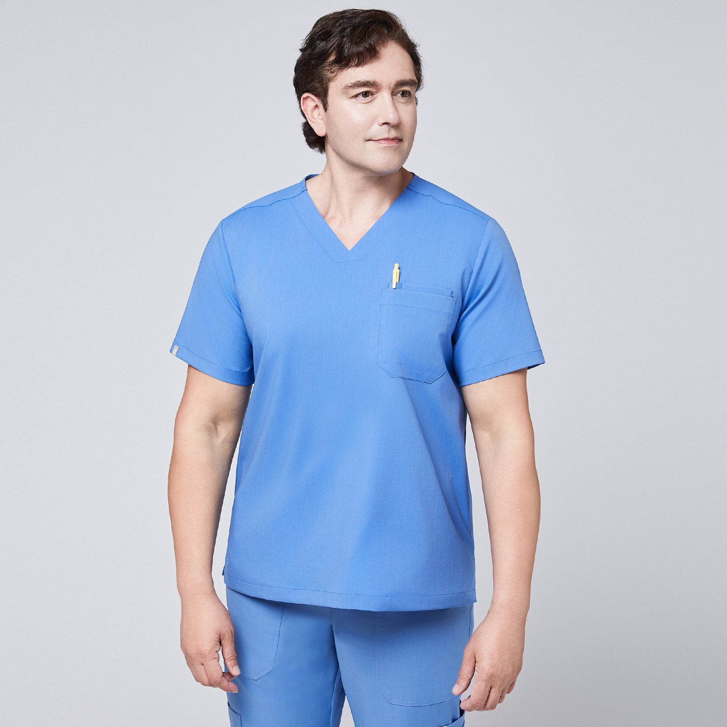 Male model wearing a ceil blue V-neck scrub set with a chest pocket holding a yellow pen, designed for a professional and clean medical uniform appearance,Ceil Blue