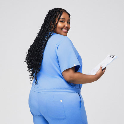 Plus-size model wearing a celi blue 3-pocket scrub top, holding a clipboard and smiling, ideal for healthcare professionals,Ceil Blue