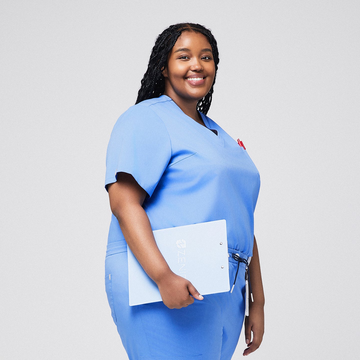 Plus-size model in light blue 3-pocket scrub top, holding a clipboard, showcasing a professional and comfortable healthcare uniform,Ceil Blue