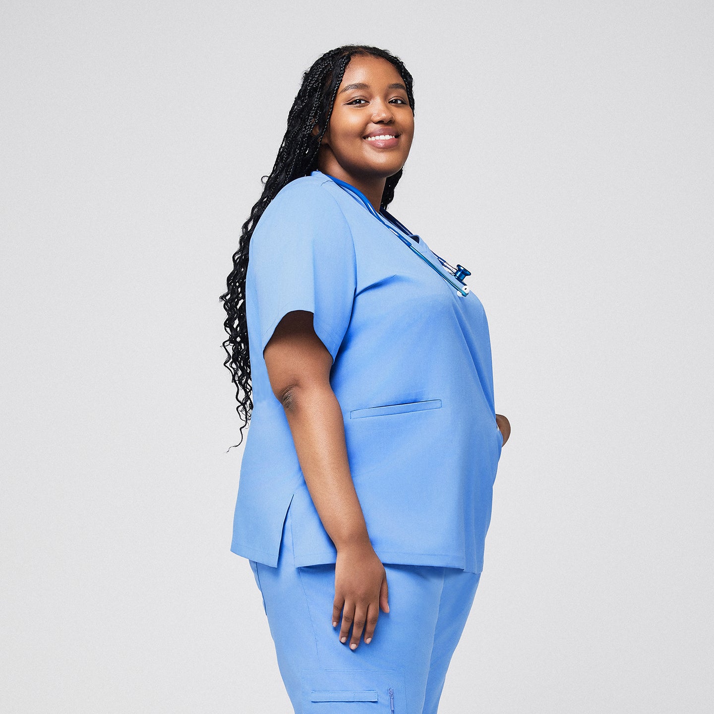 Side view of a plus-size healthcare professional in a ceil blue scrub set, smiling with a stethoscope around the neck,Ceil Blue