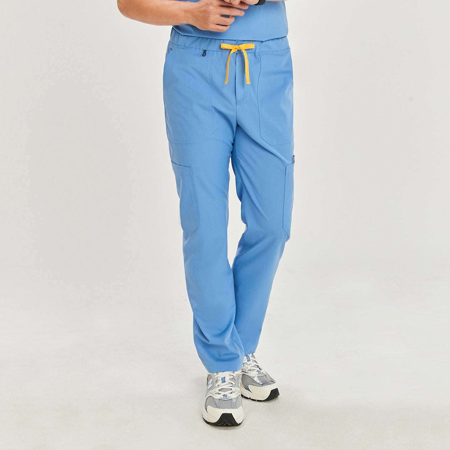 Front view of a model wearing ceil blue zipper straight scrub pants with zipper details, a yellow drawstring, and a matching top, paired with white athletic shoes,Ceil Blue