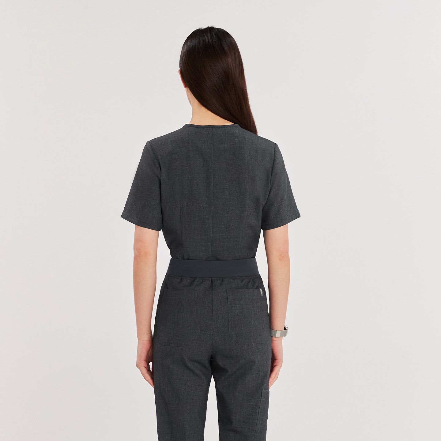 Model facing away, wearing a V-neck scrub top and matching pants with a drawstring waist,Charcoal Gray