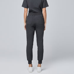 Image of Back view of charcoal gray jogger scrub pants with rear pockets, elastic waistband, and cuffed ankles, paired with white sneakers,Charcoal Gray