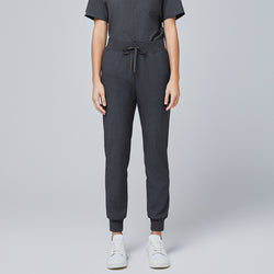 Image of Front view of charcoal gray jogger scrub pants with an elastic waistband, adjustable drawstring, and cuffed ankles, paired with white sneakers,Charcoal Gray