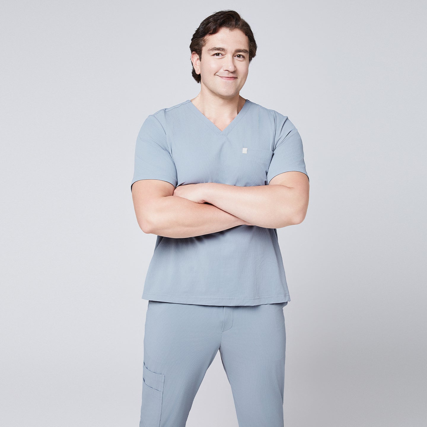 Man wearing a cool gray scrub set with arms crossed, featuring a single-pocket V-neck top,Cool Gray