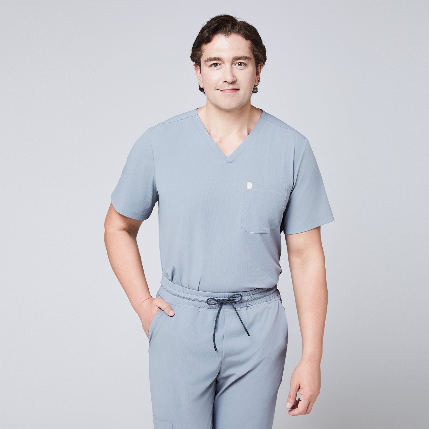 Man wearing a cool gray scrub set with arms crossed, featuring a single-pocket V-neck top,Cool Gray