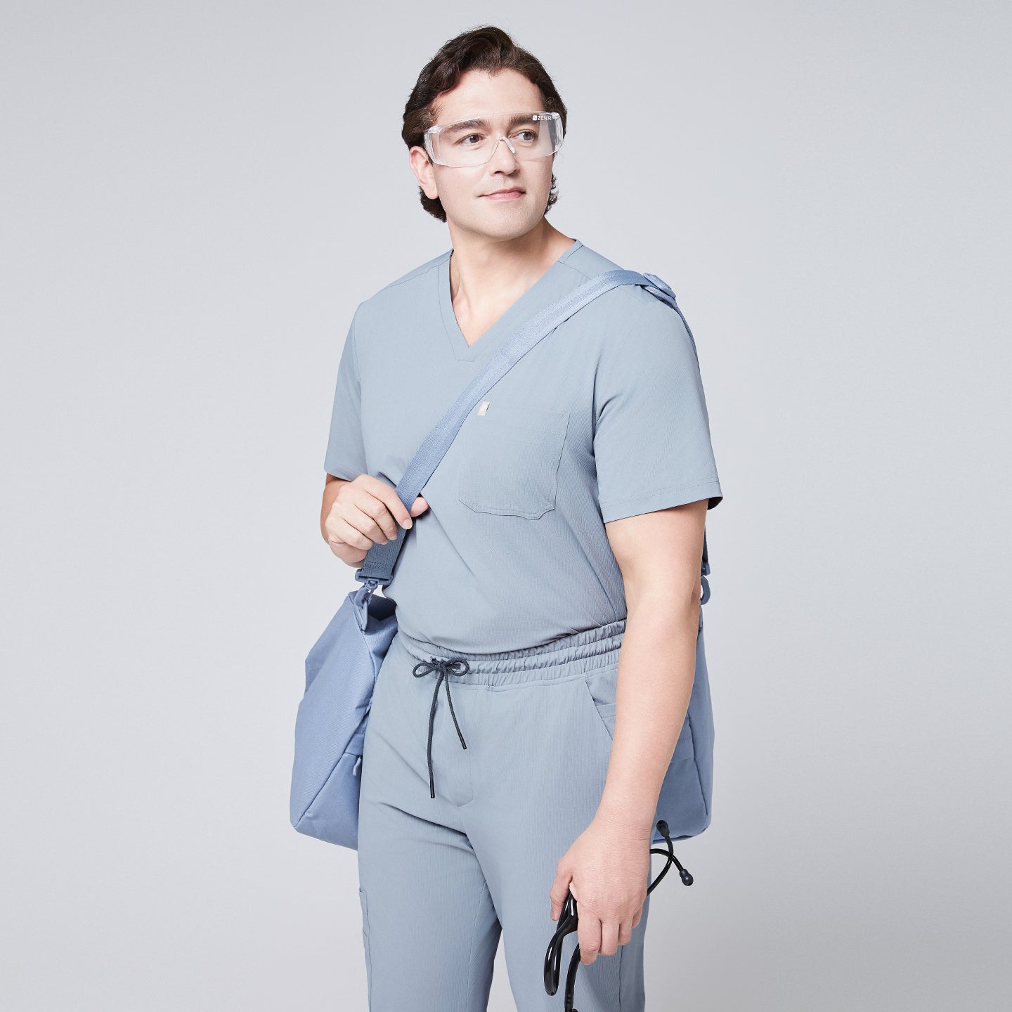 Man in a cool gray scrub set, wearing protective glasses and carrying a matching shoulder bag and stethoscope,Cool Gray