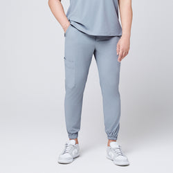 Image of Front view of cool gray jogger scrub pants with a cargo pocket and elastic cuffs, paired with gray Nike sneakers,Cool Gray