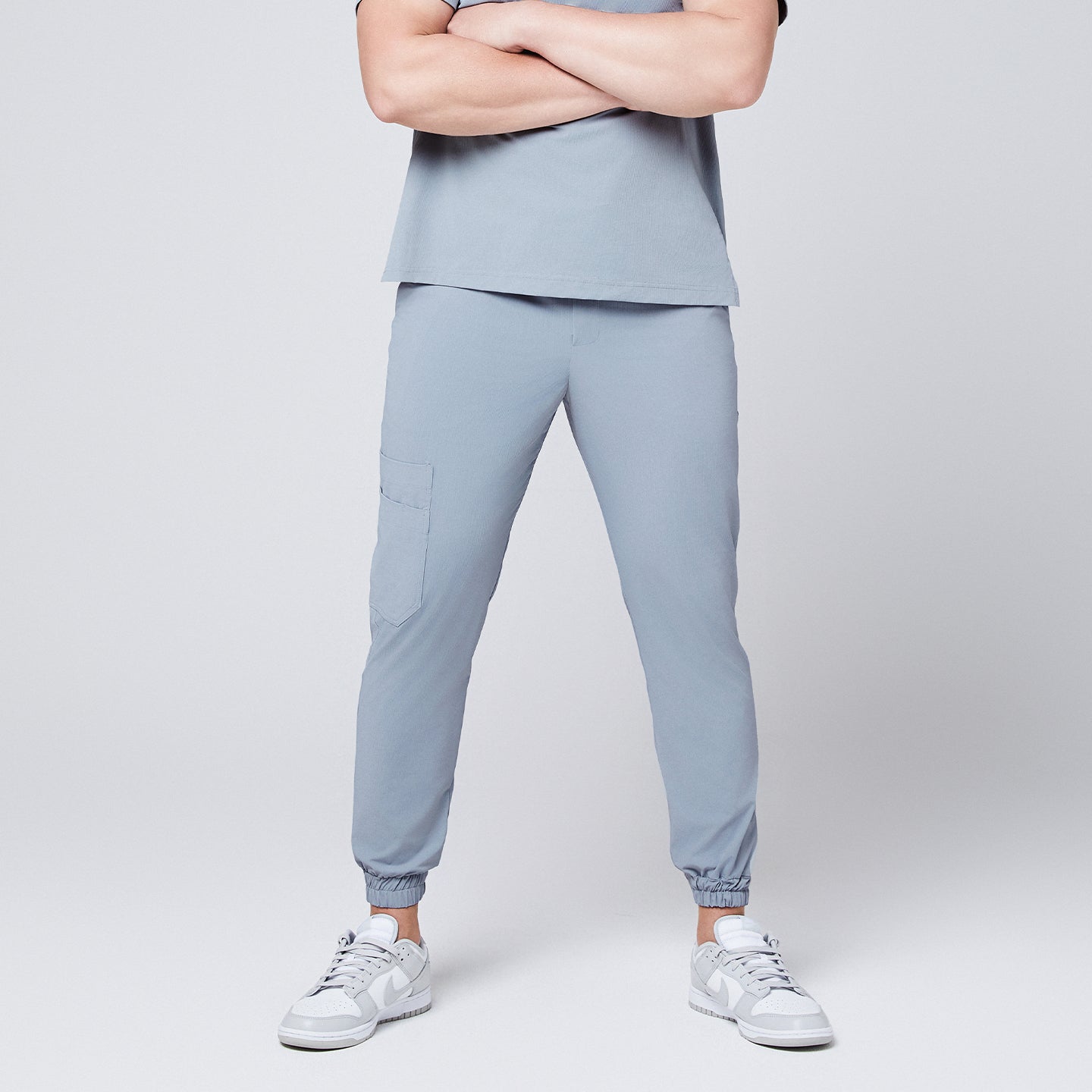 Cool gray jogger scrub pants with a cargo pocket and elastic cuffs, styled with a casual stance and paired with gray Nike sneakers,Cool Gray