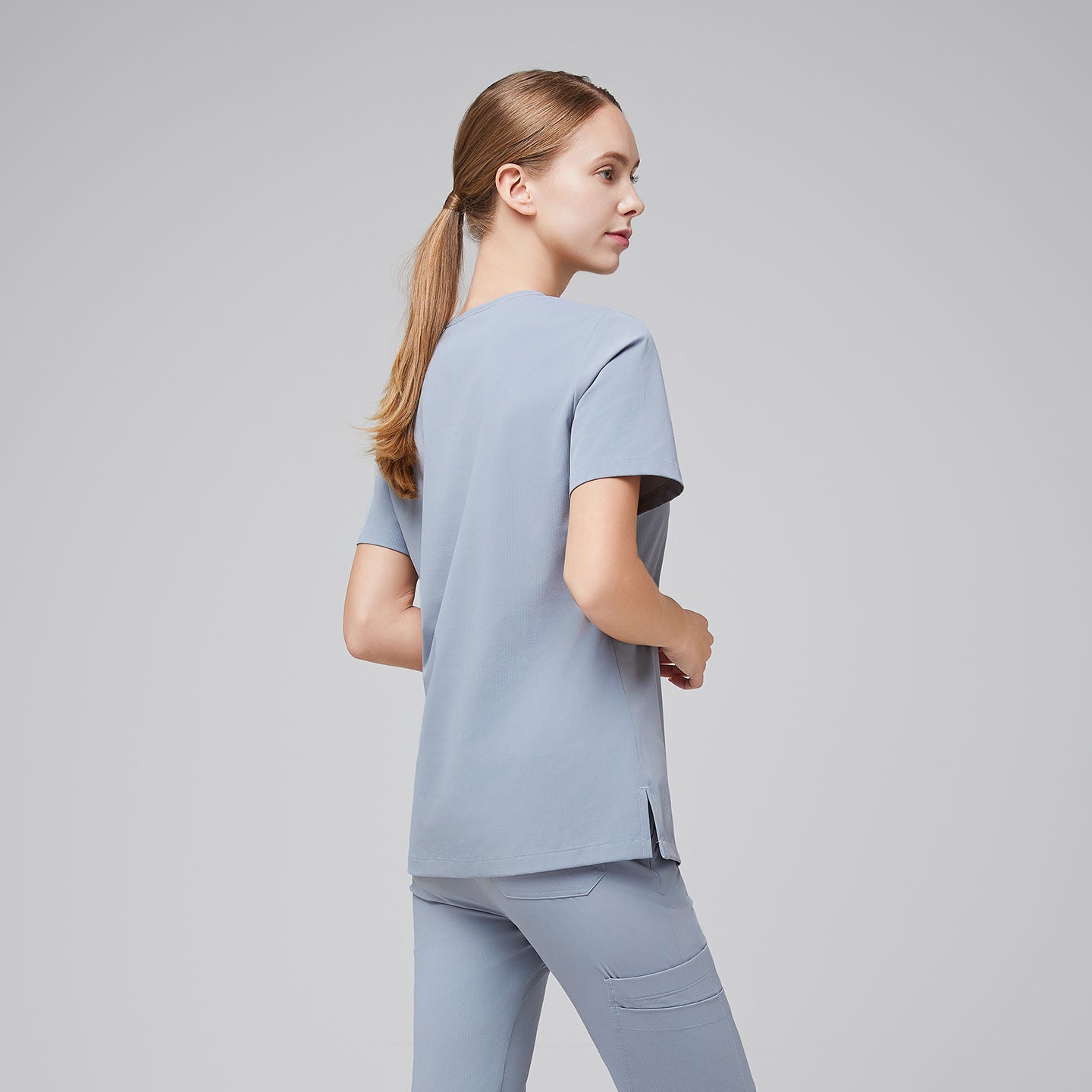 Side-back view of a female healthcare professional in a cool gray scrub set, showing the clean design and relaxed fit,Cool Gray