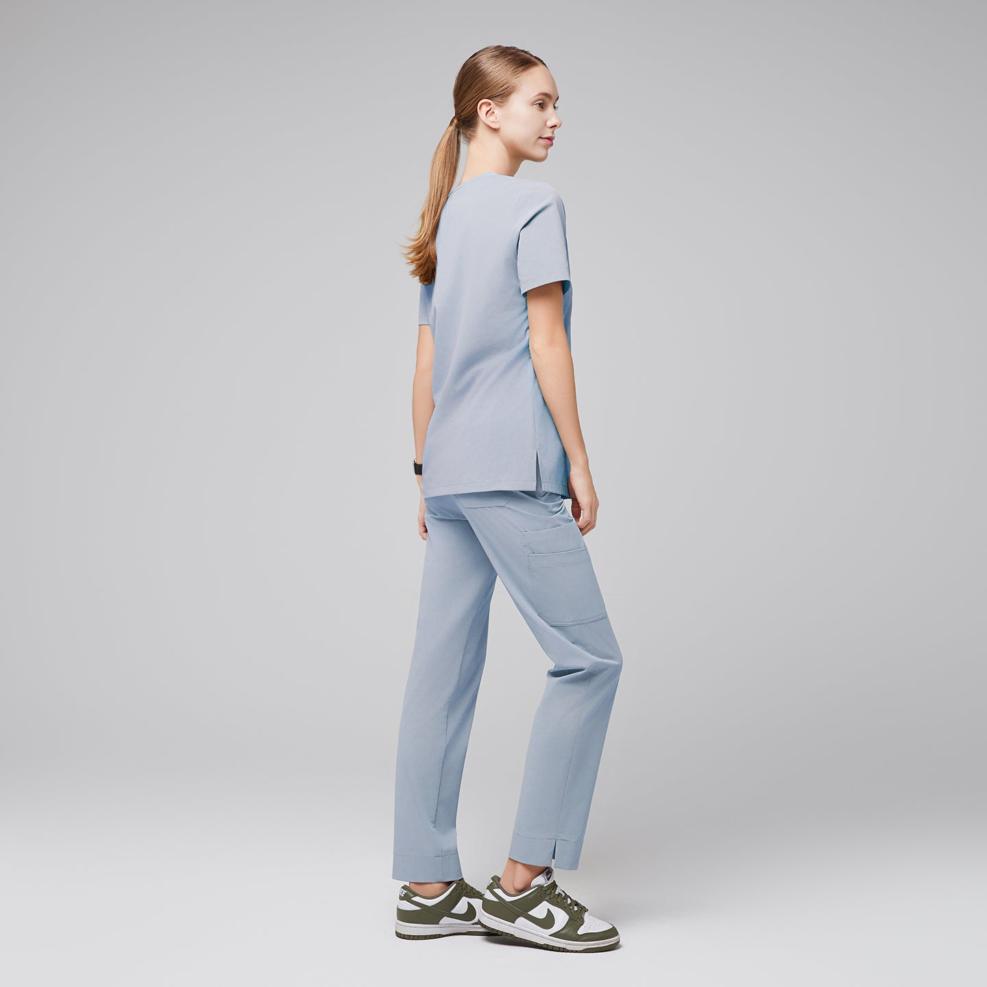 Model in cool gray scrubs, standing with back turned, wearing green and white sneakers,Cool Gray