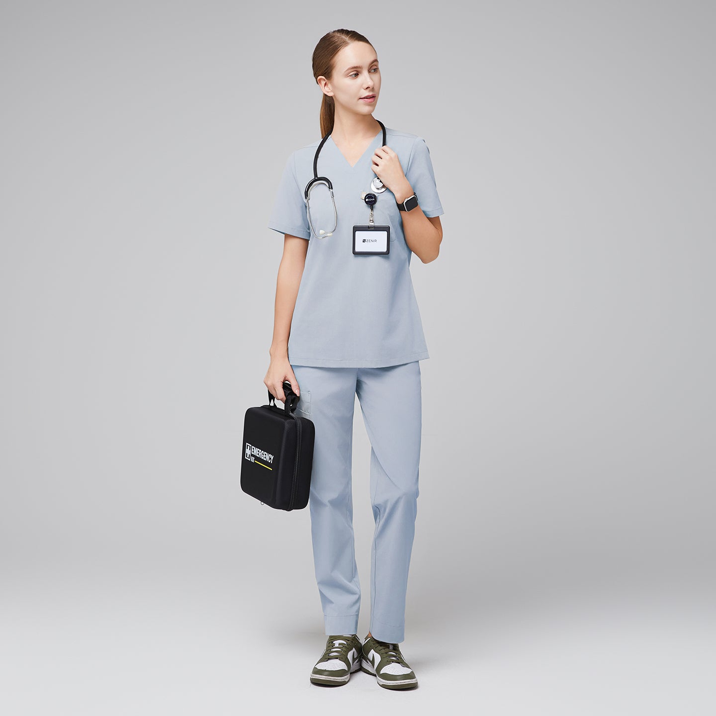 Model wearing cool gray V-neck scrub top and straight-leg scrub pants, holding a medical kit and stethoscope,Cool Gray