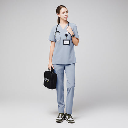 Female healthcare professional in gray scrubs holding an emergency kit with a stethoscope and ID badge,Cool Gray